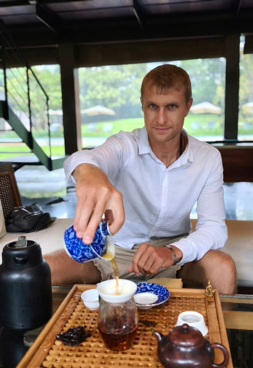 一位男子将茶倒入茶盘上的玻璃公道杯中